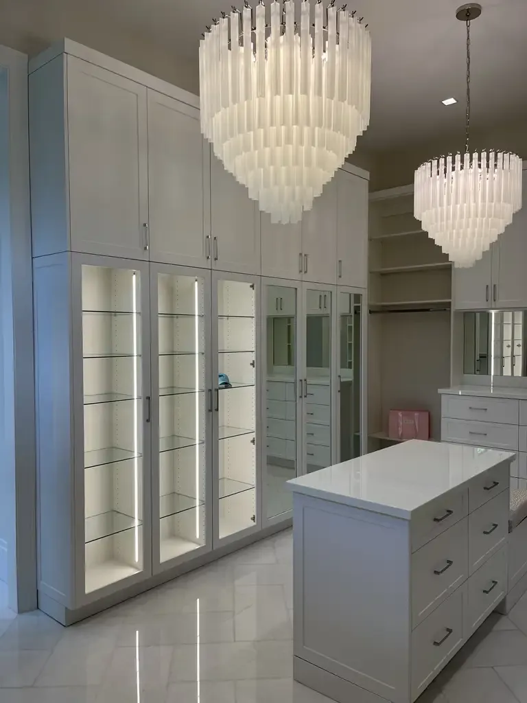 Luxury white walk-in closet with glass display cabinets by Kitchen & Bath Studios Inc.