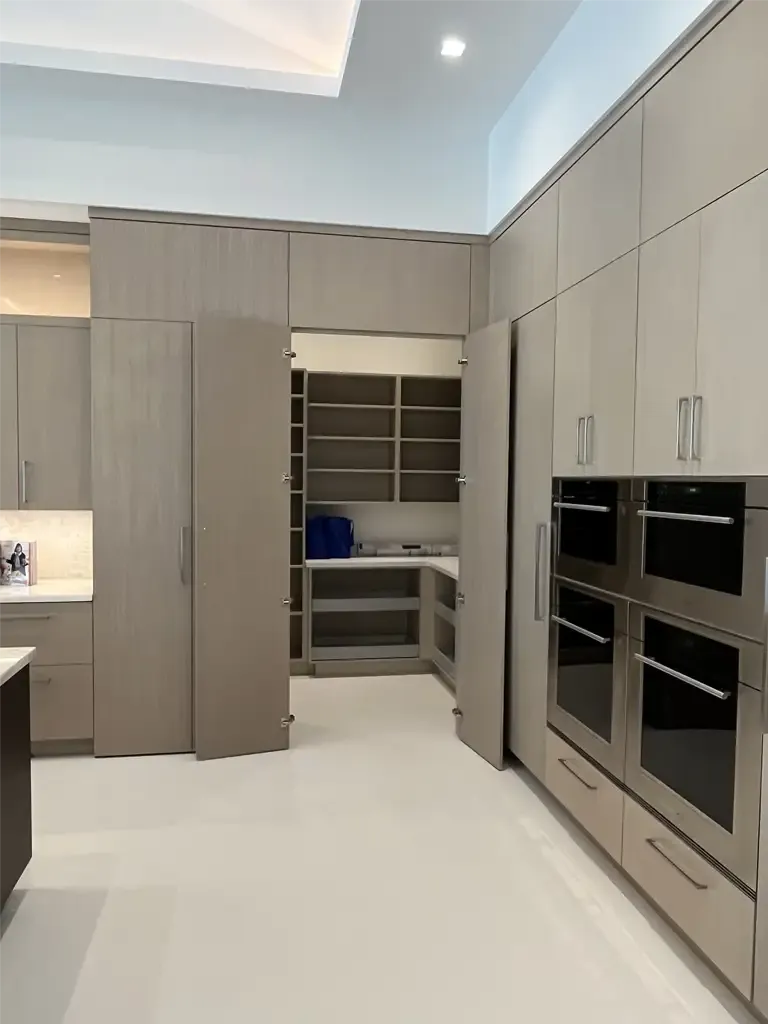 Modern kitchen featuring hidden walk-in pantry and wall ovens by Kitchen & Bath Studios Inc.