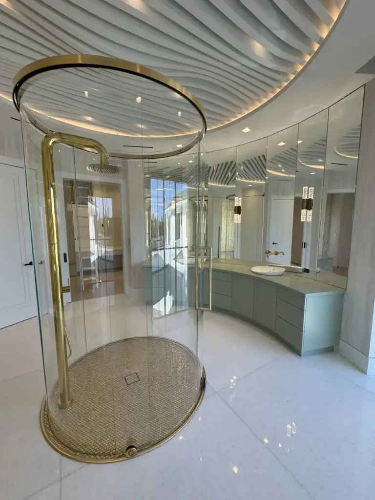 Luxury round glass shower with gold fixtures by Kitchen & Bath Studios Inc.