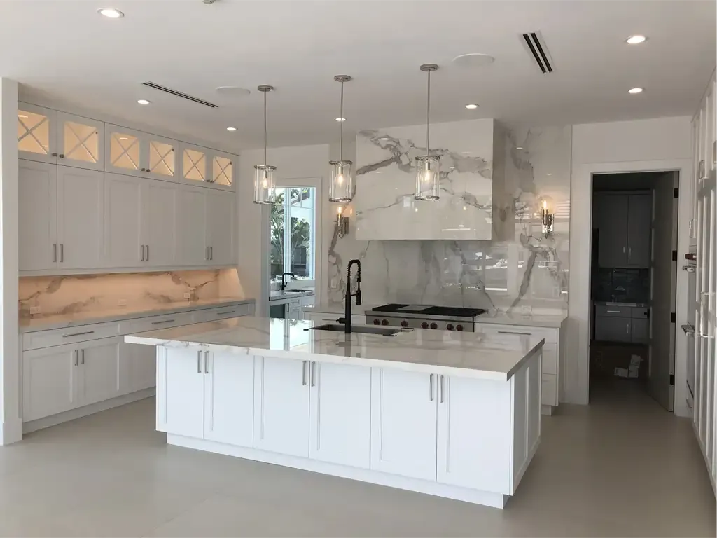 White kitchen with glass upper cabinets and marble slab by Kitchen & Bath Studios Inc.