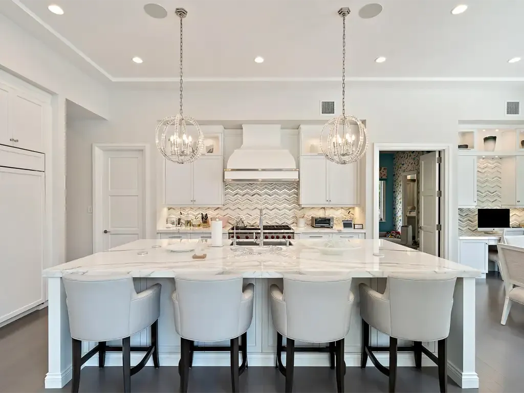 Luxury white kitchen island and globe lights by Kitchen & Bath Studios Inc.