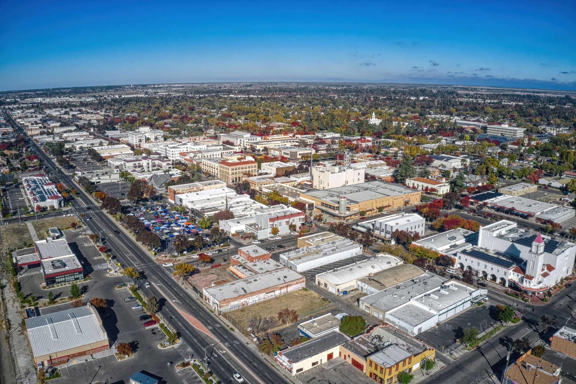 Aerial view of a sprawling city neighborhood with streets, low-rise buildings, and a clear blue sky.