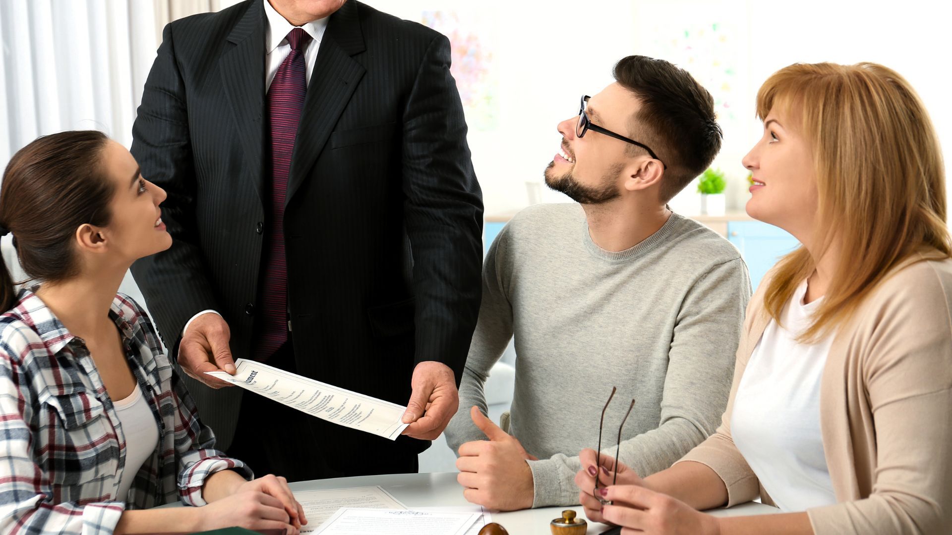 Group of people looking at paperwork, a man in a suit holds the document.