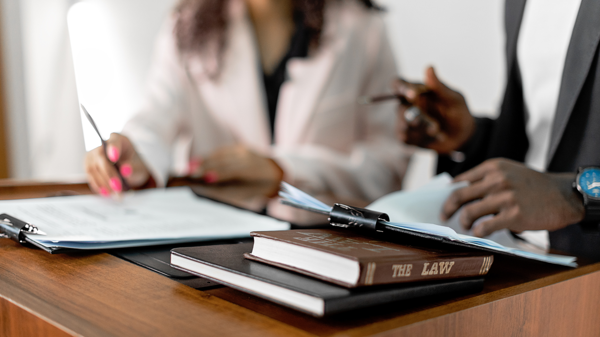 People reviewing documents, law book on a desk.