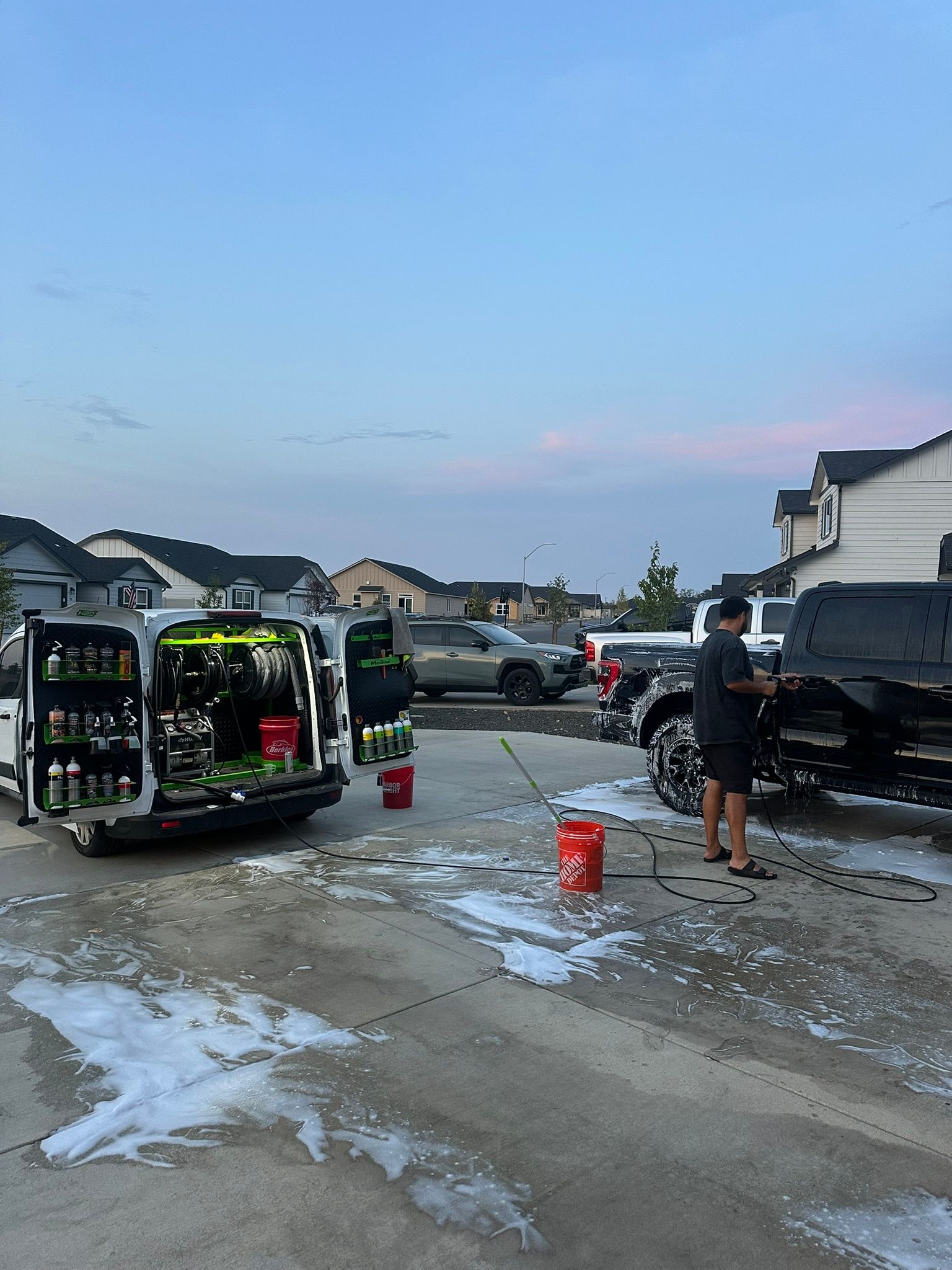 OG Pro Detail self-contained mobile unit set up on site with hoses running while a technician washes a pickup truck