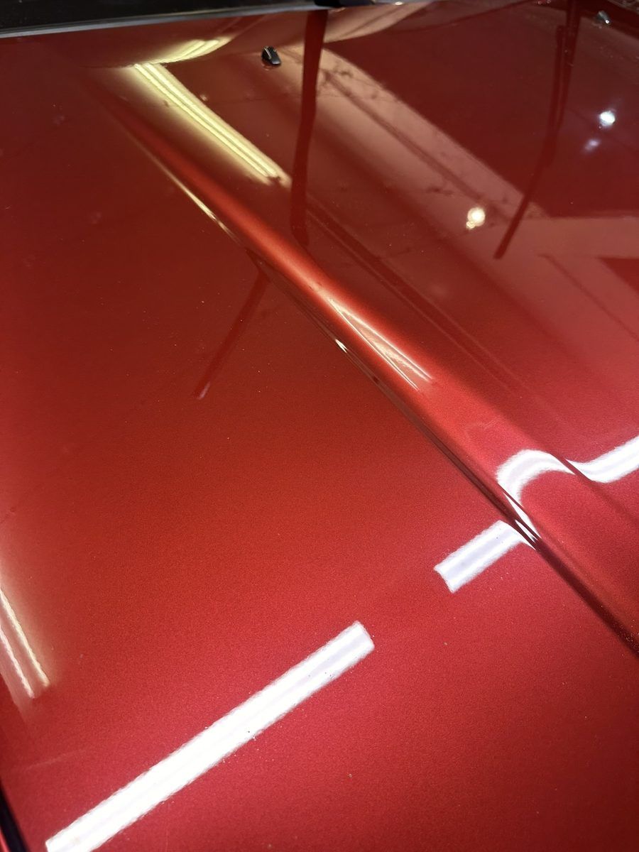 Close-up of glossy red paint with clear, sharp reflections after polishing by OG Pro Detail