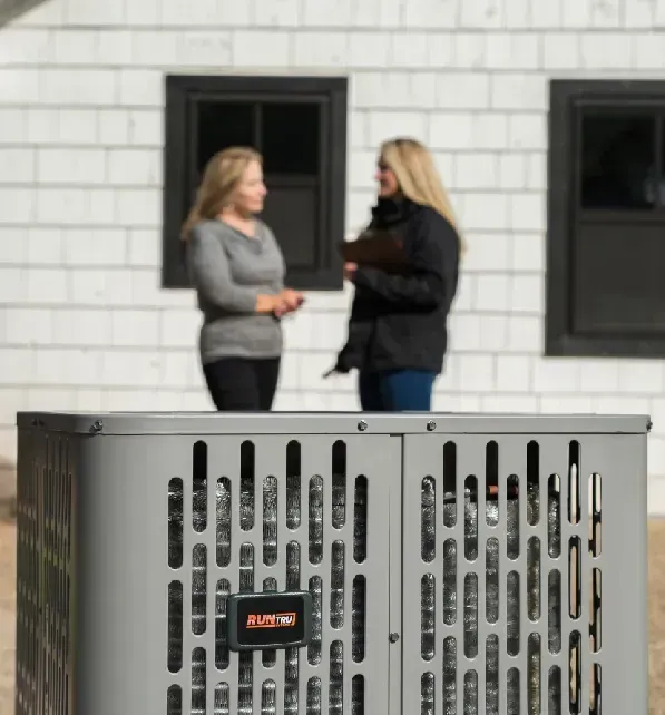 Two people talking outside a building, with a metal utility box in the foreground