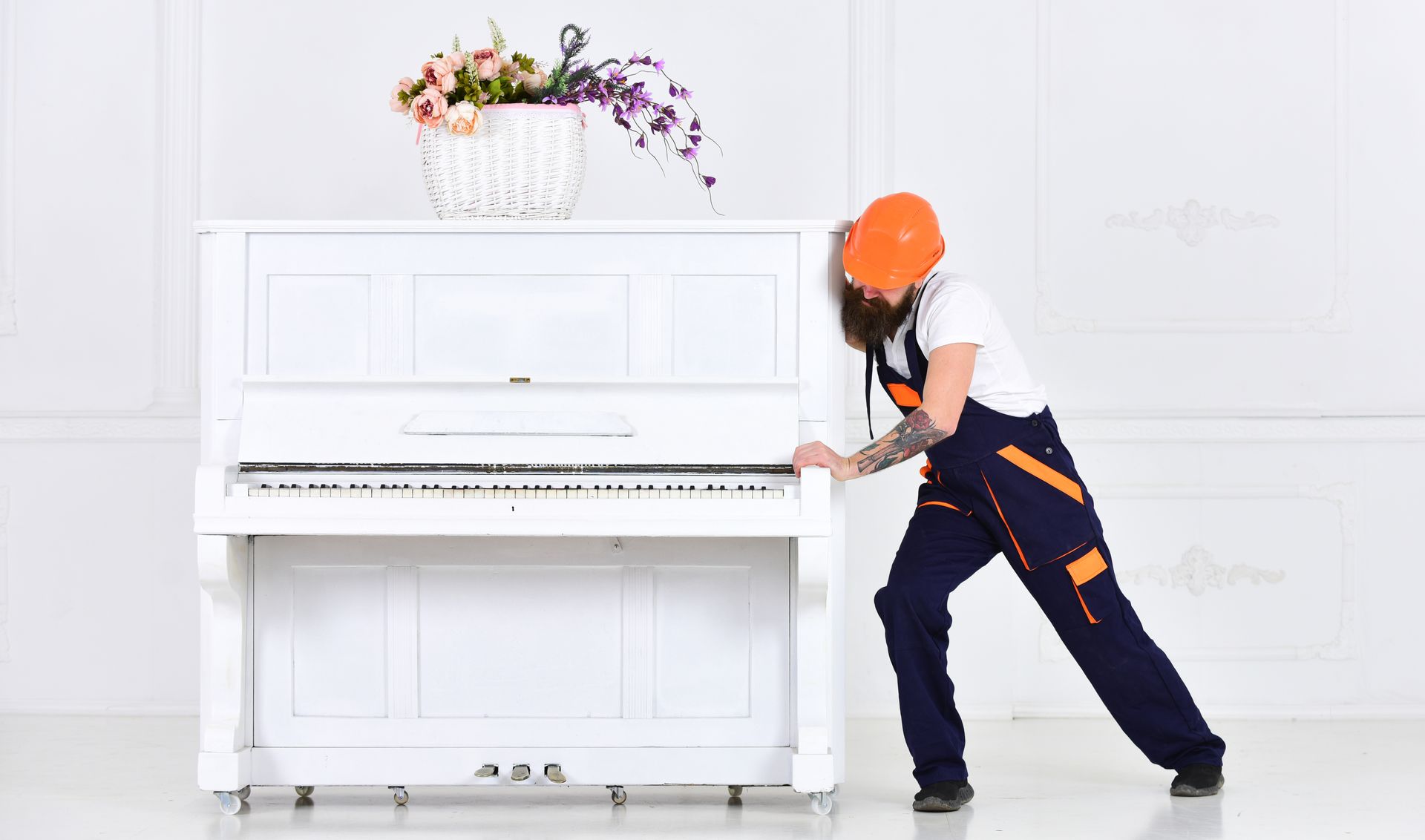 Mover pushing an upright piano across a room during relocation.