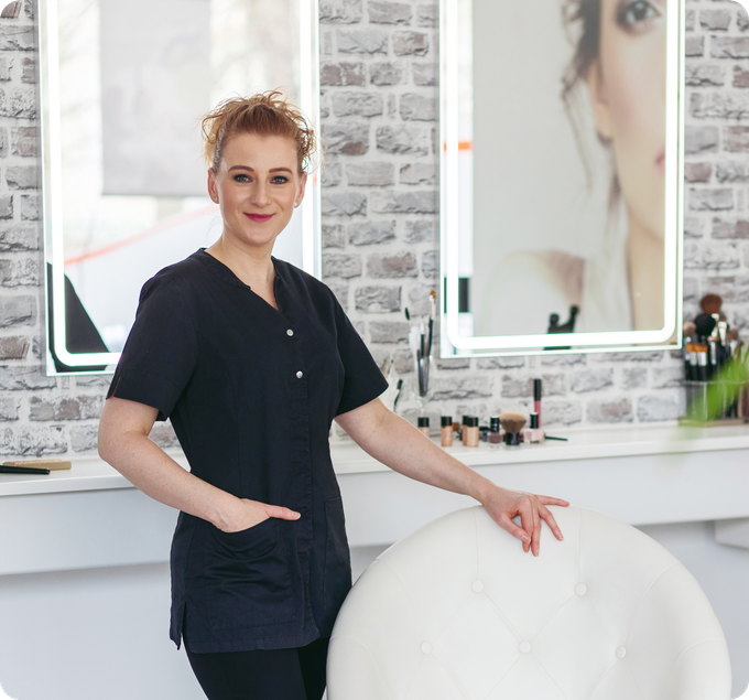 Eine Frau steht in einem Salon vor einem Spiegel.