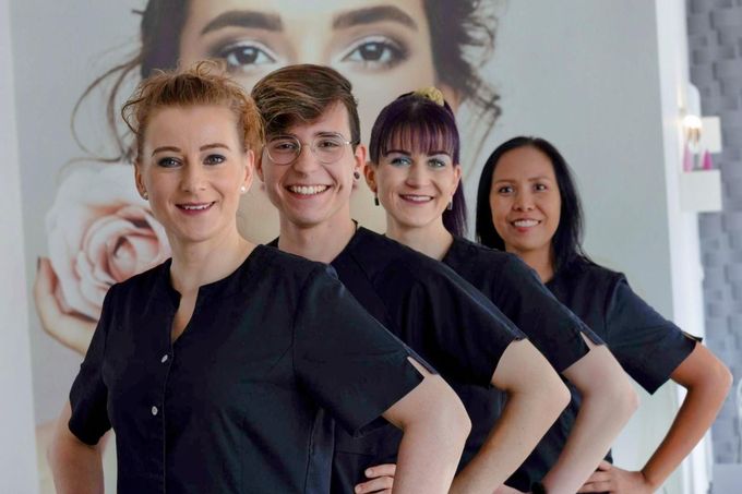 Eine Gruppe von Menschen posiert für ein Foto vor dem Gesicht einer Frau.