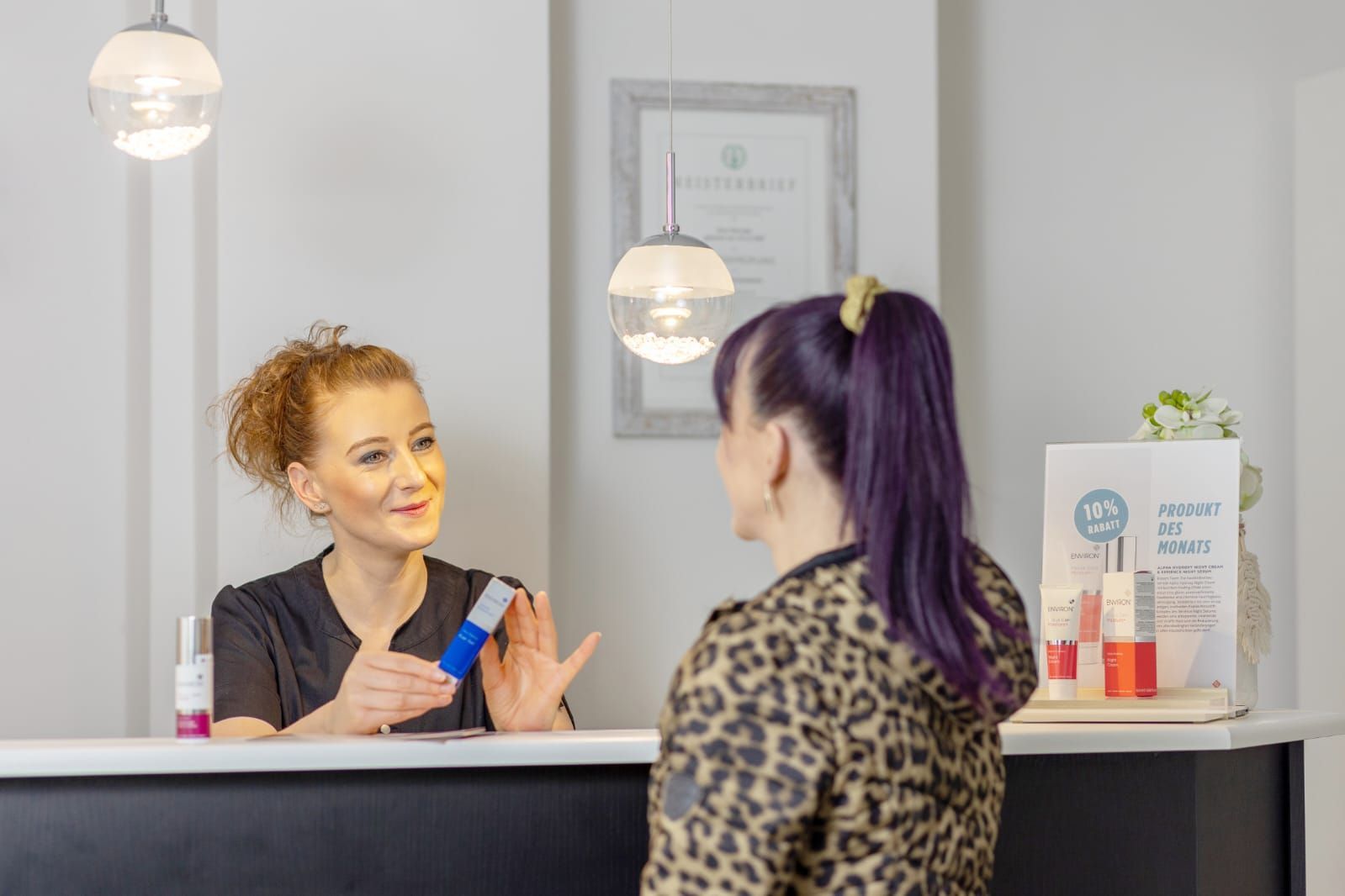 Eine Frau spricht mit einer anderen Frau an einem Tresen in einem Salon.