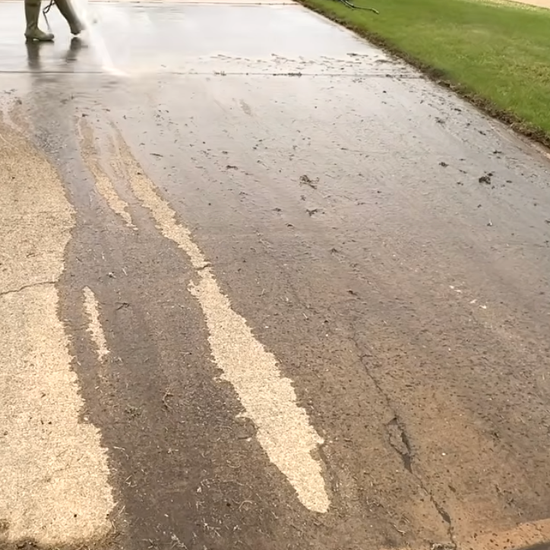 A person is cleaning a dirty sidewalk with pressure washer.