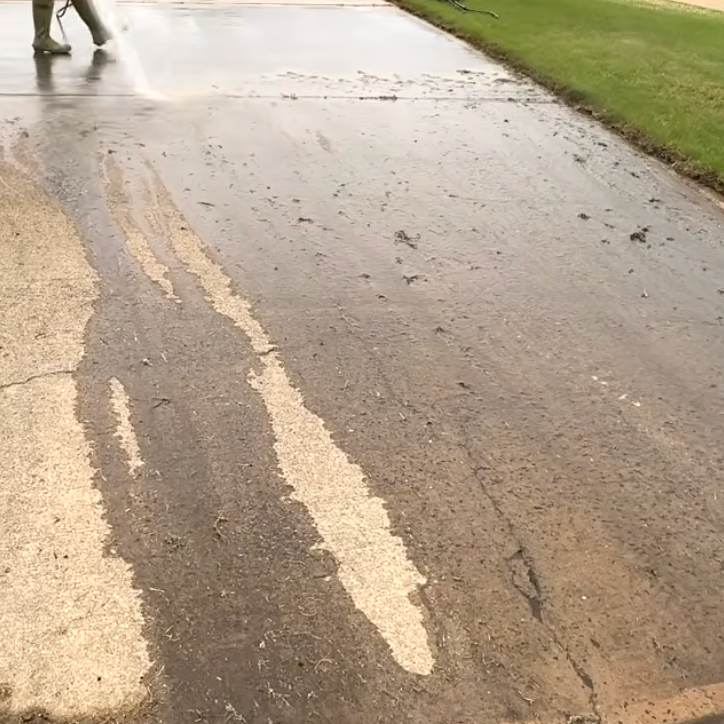 A person is cleaning a sidewalk using pressure washer.