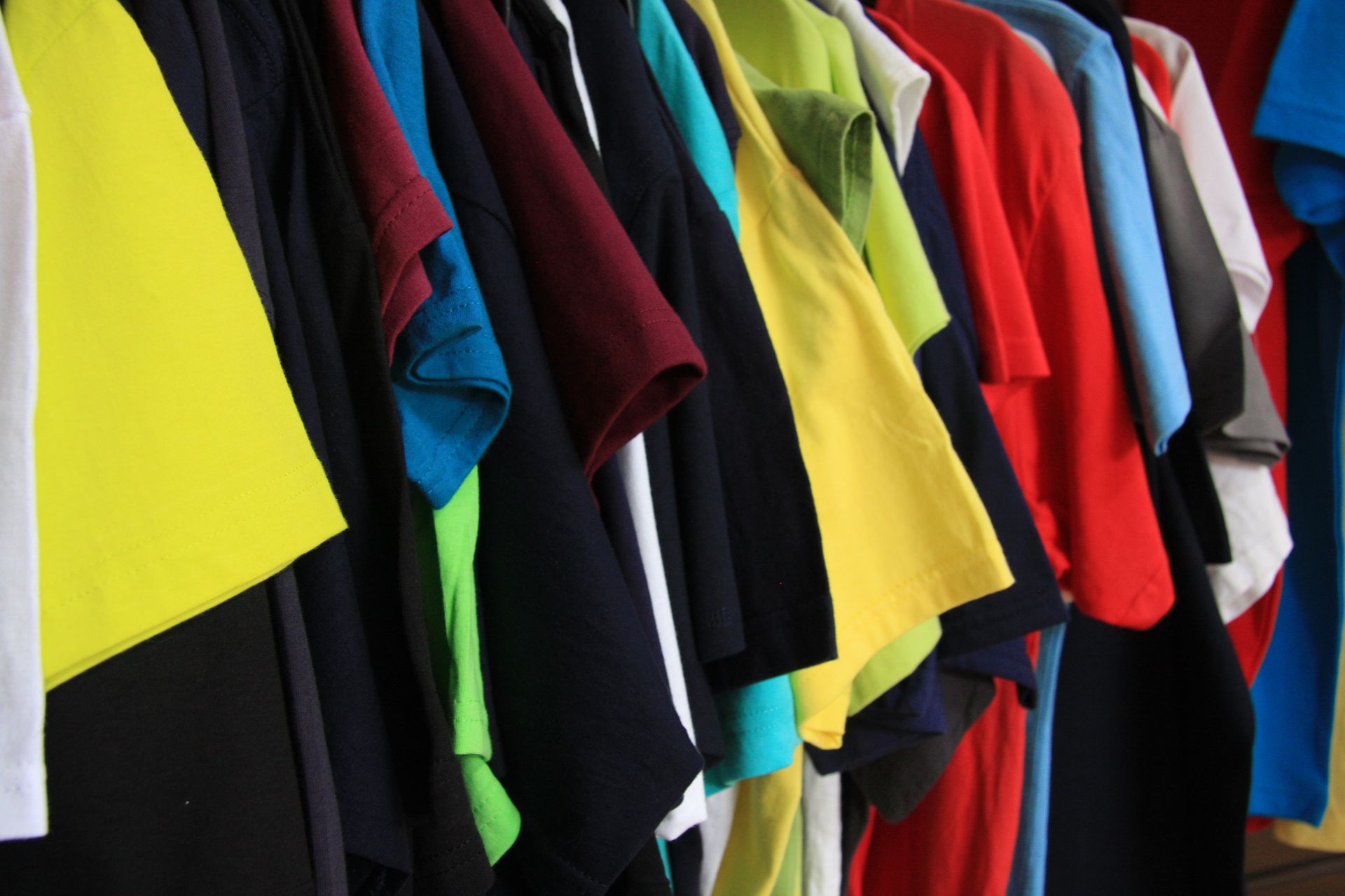 Ein Haufen verschiedenfarbiger T-Shirts hängt an einem Ständer