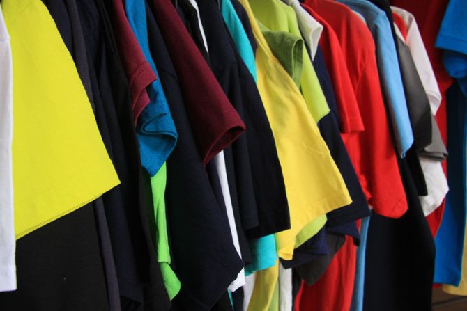 Ein Haufen verschiedenfarbiger T-Shirts hängt an einem Ständer