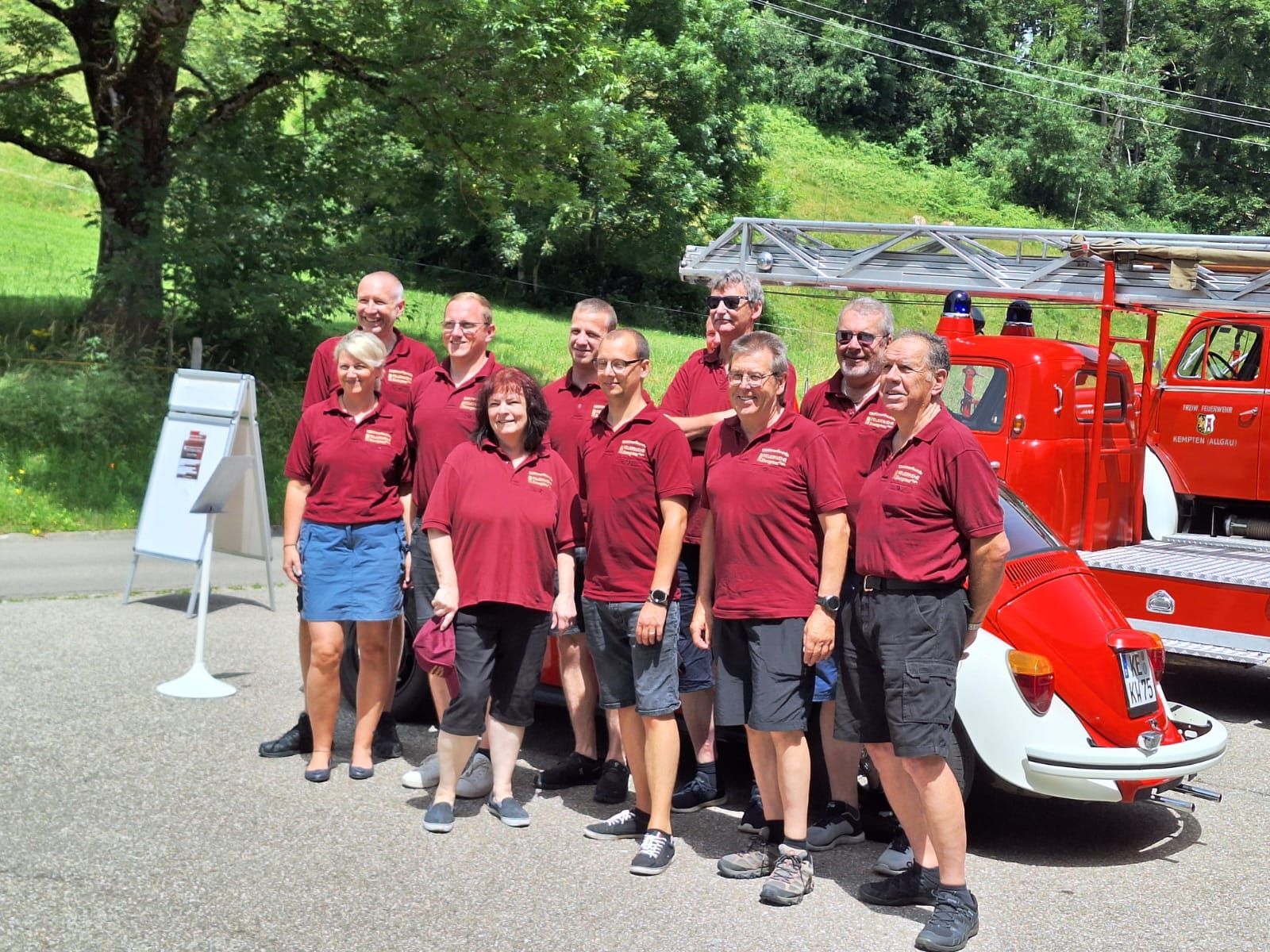Eine Gruppe von Menschen in denselben Shirts steht vor einem roten Feuerwehrauto.