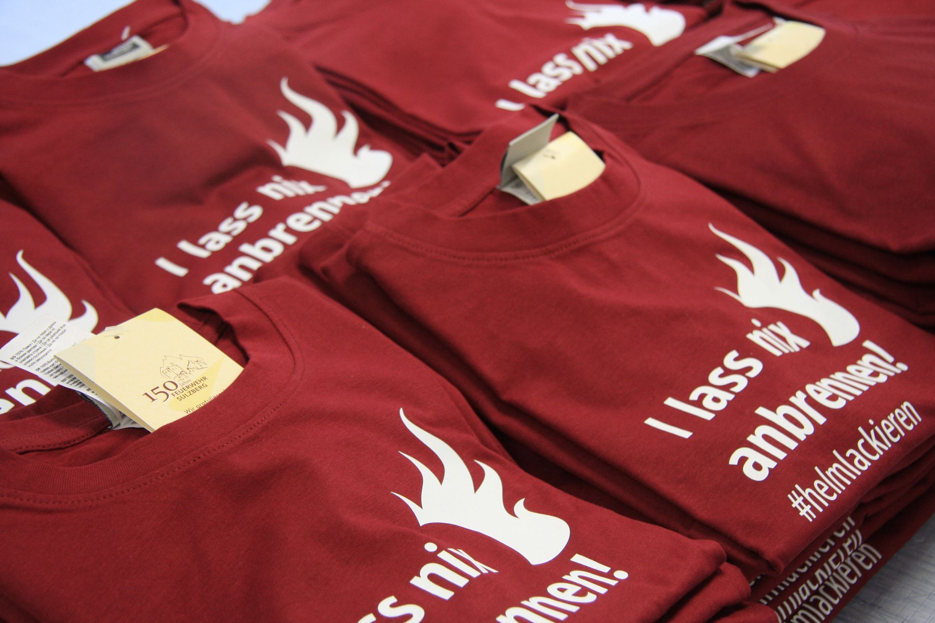 Ein Haufen roter T-Shirts mit weißer Aufschrift