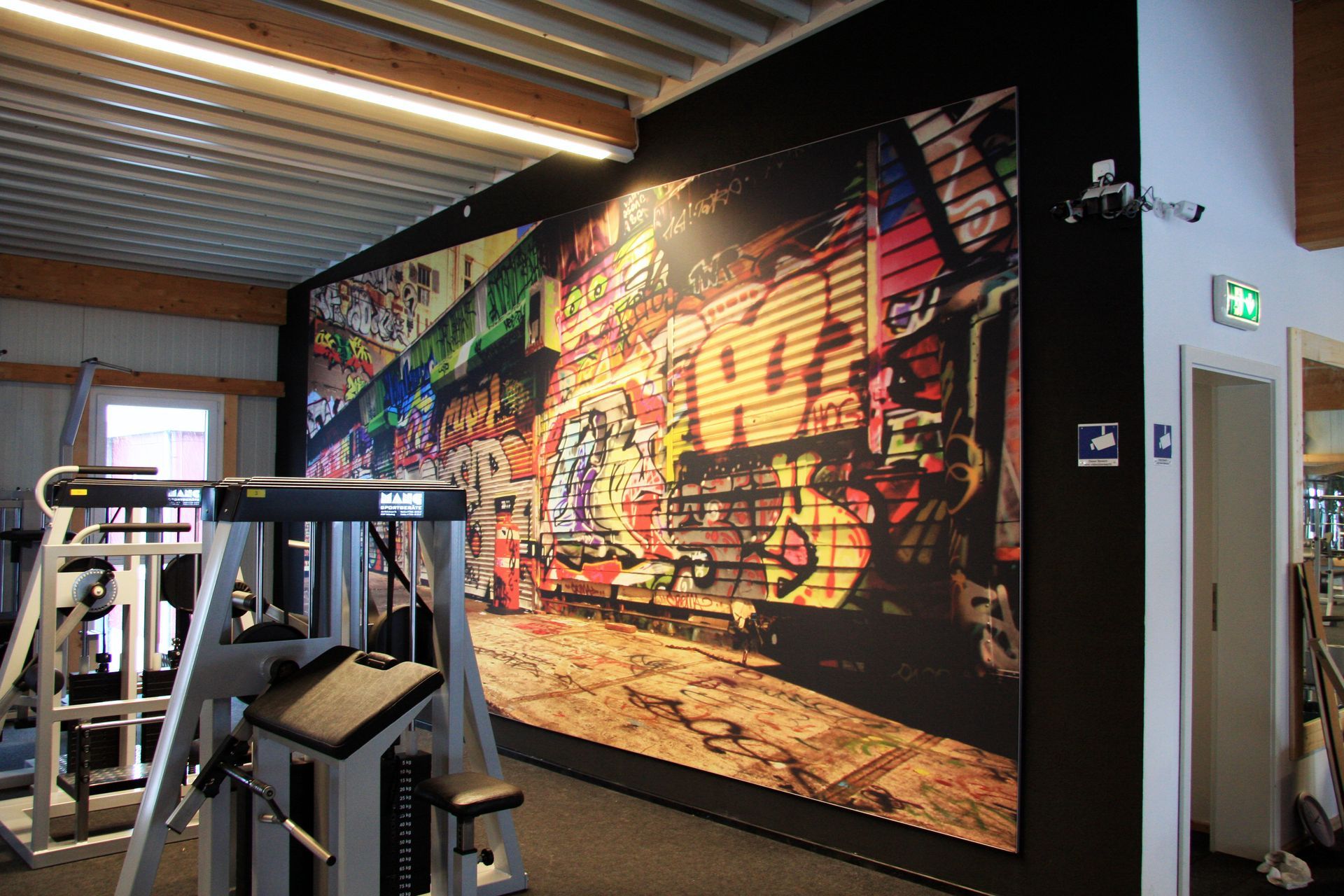 Ein Fitnessstudio mit einem großen Wandbild an der Wand