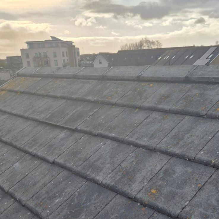 A roof with a lot of tiles on it and a building in the background.