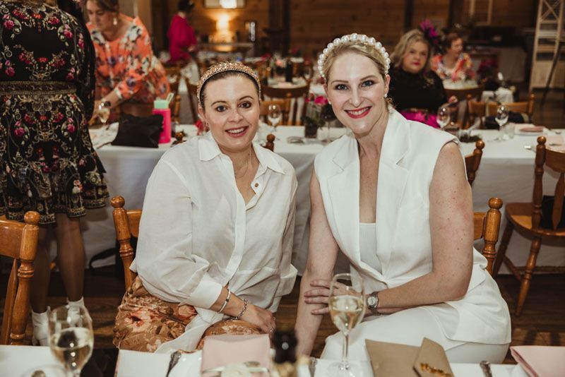 Two women are sitting at a table with glasses of wine.