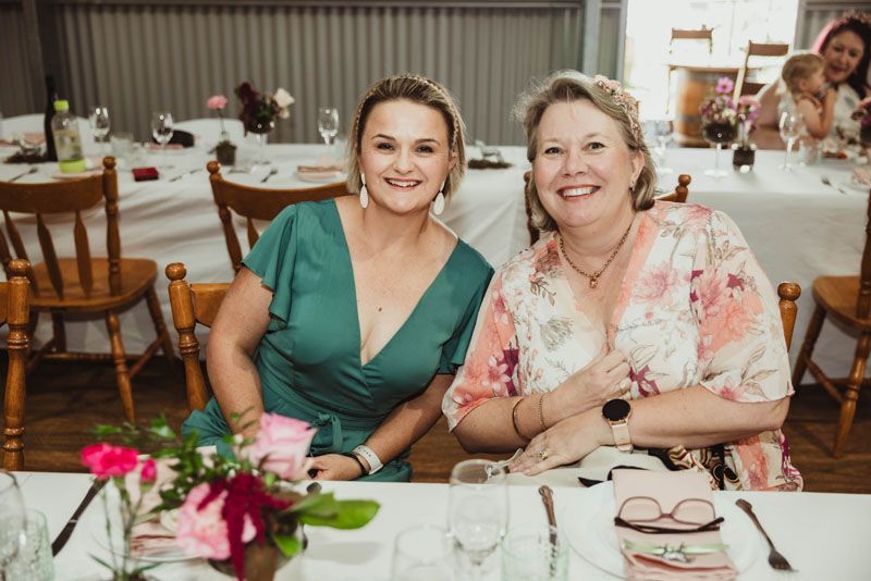 Two women are sitting at a table with glasses of wine.