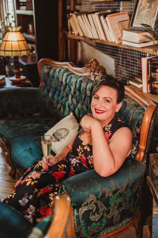A woman is sitting on a couch holding a glass of champagne.