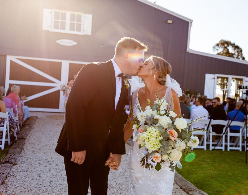 A bride and groom are kissing in front of Aberfeldy Barn.