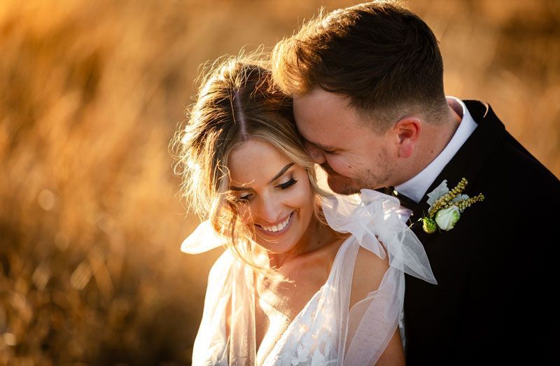 A bride and groom are posing for a picture in a field.