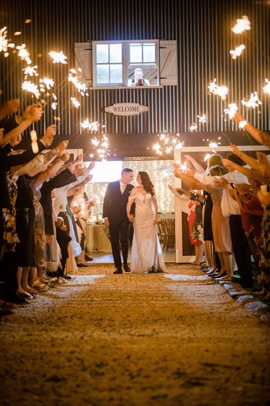 A bride and groom are walking through a tunnel of sparklers outside Aberfeldy Barn