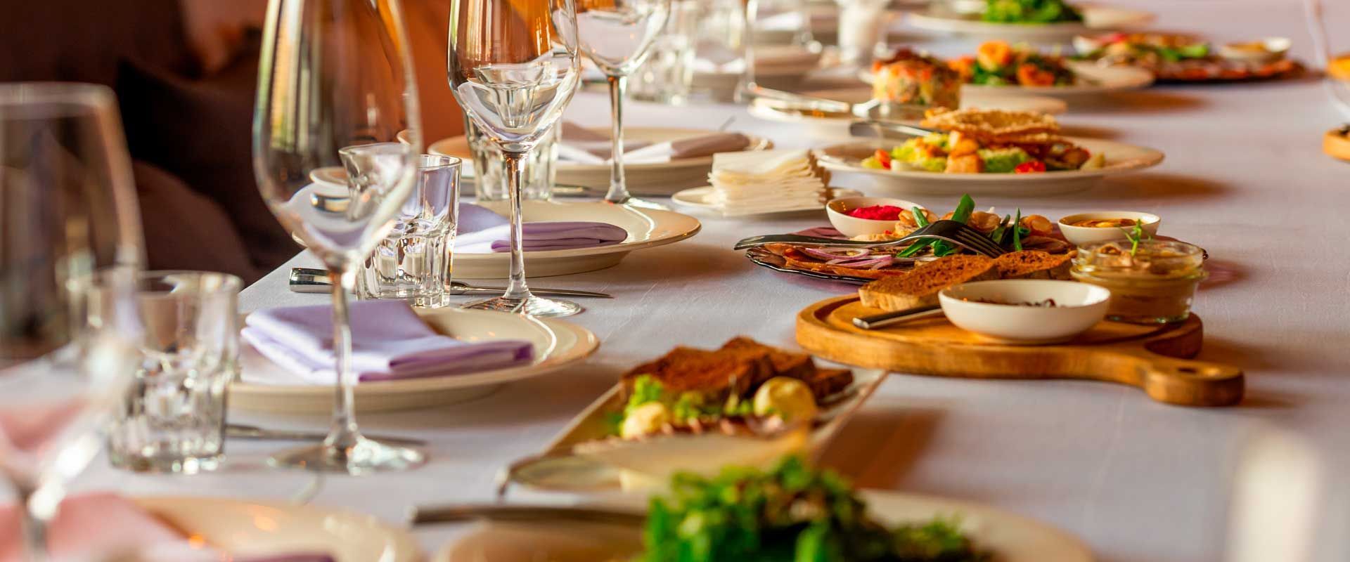 A long table set with food and drinks for a formal dinner.