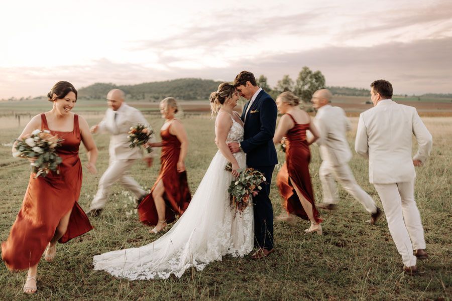 A bride and groom are standing in a field with their wedding party.