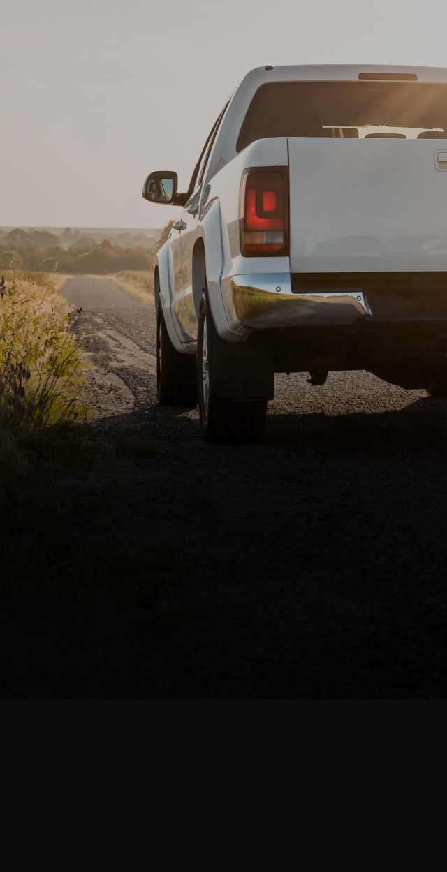 White pickup truck parked on a desert roadside at sunset