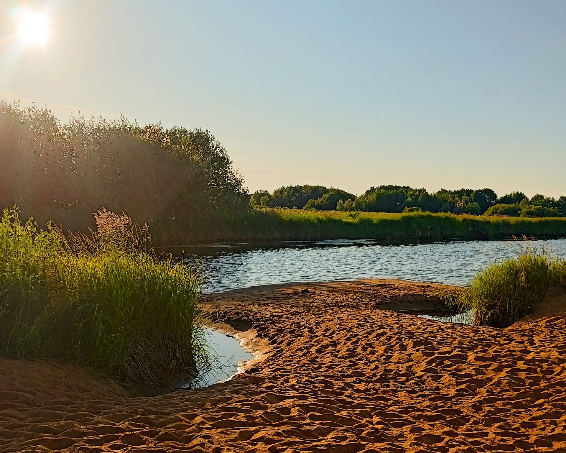 Sandy beaches and Ounasjoki river with blue skies and summer plants