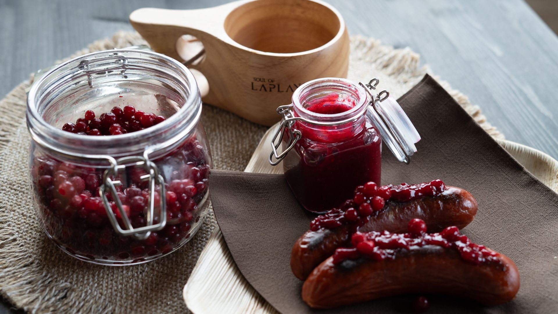 Reindeer sausage with lingon berry jam and kuksa and a jar of fresh lingon berries.