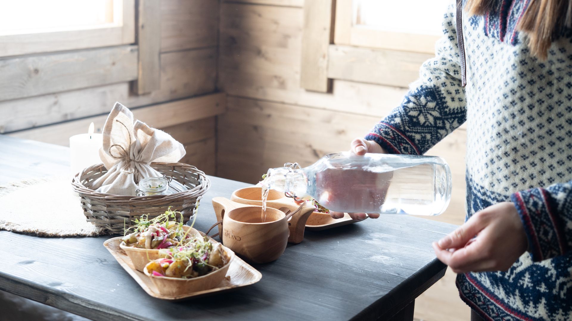 Woman serving a table in traditional wooden cabin
