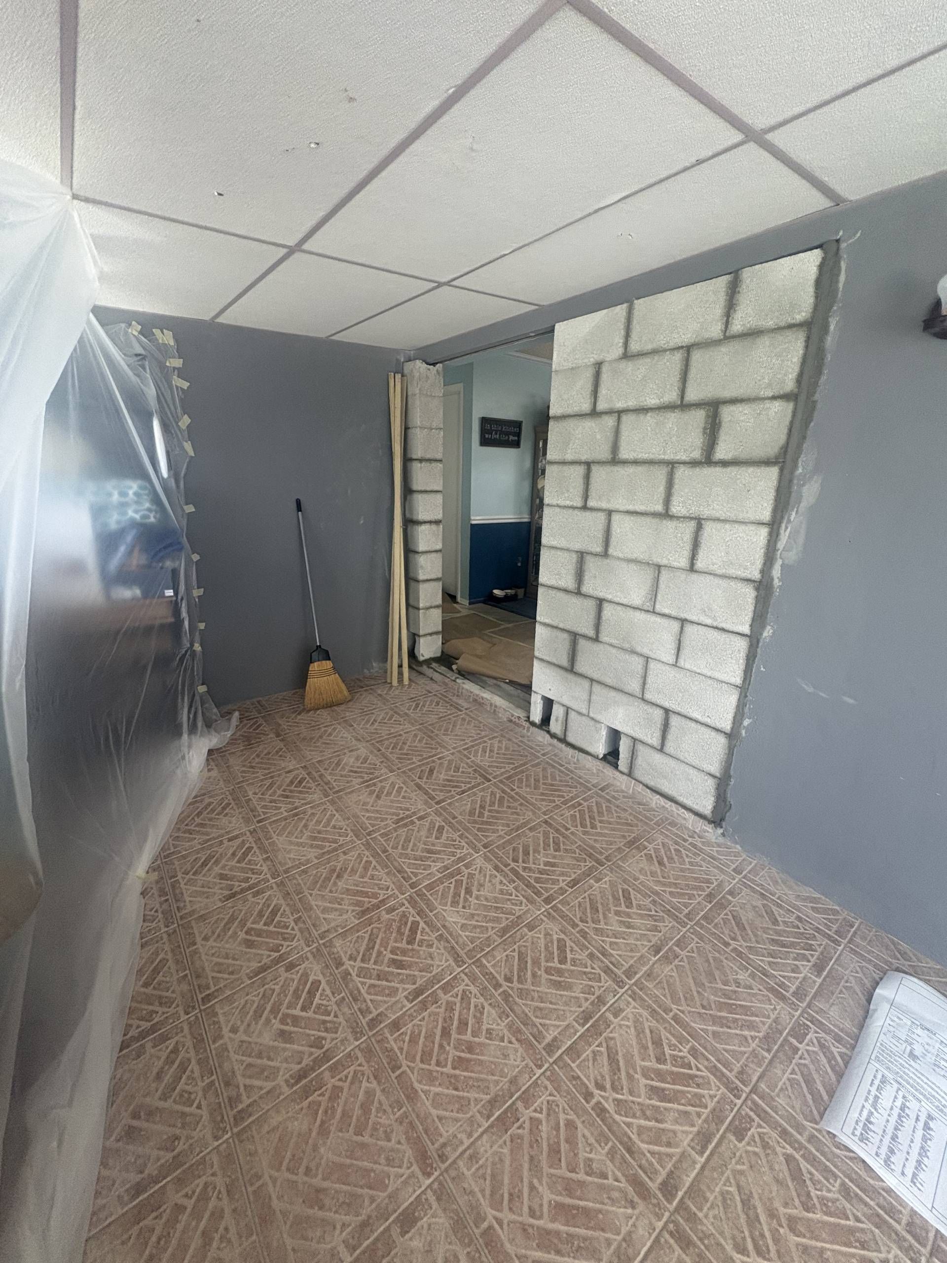 Narrow finished hallway with gray walls, tiled floor, and a concrete masonry block unit partition near a doorway.