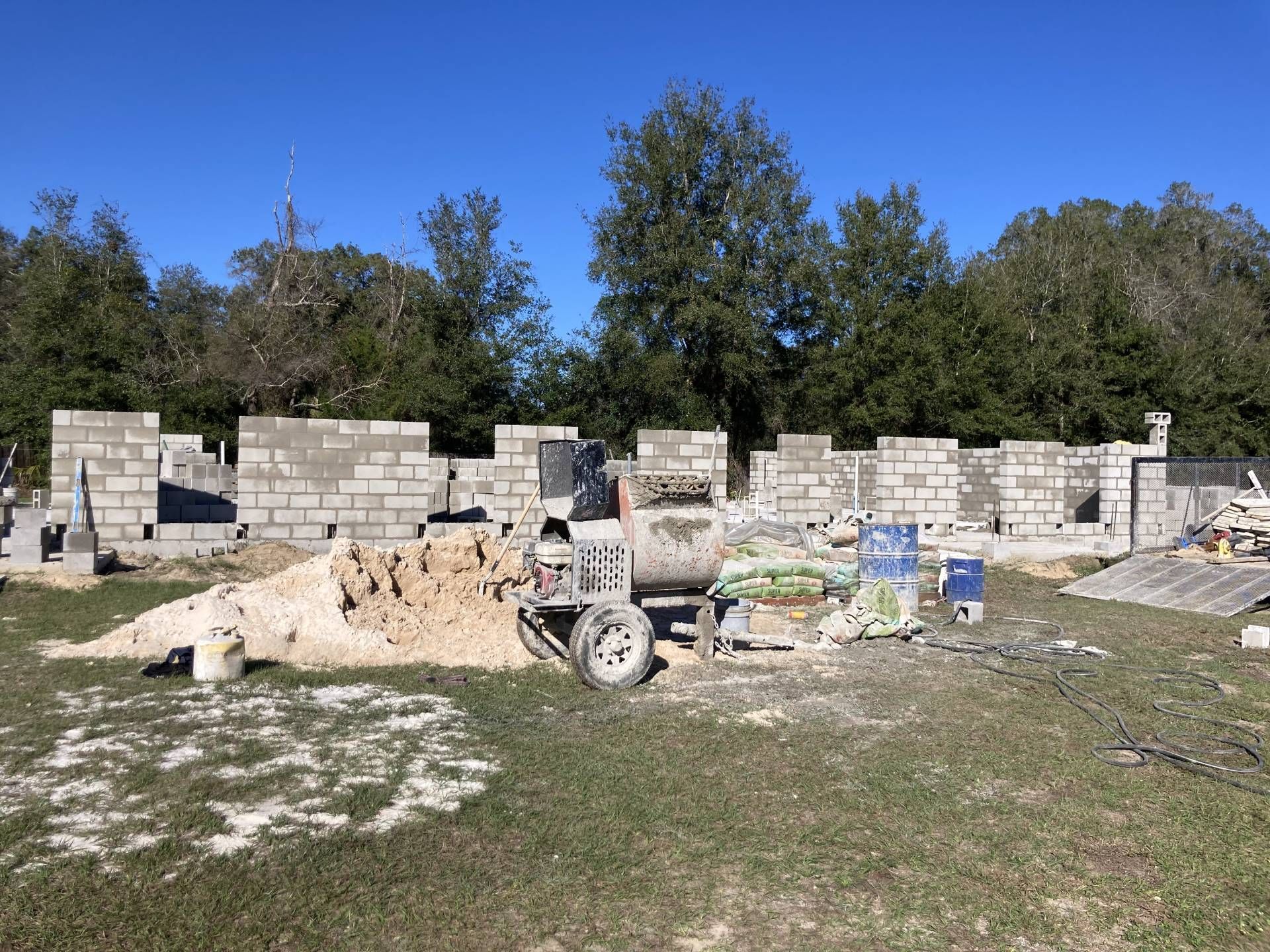 fully built concrete masonry unit block structure with construction materials on a grassy lot under a blue sky
