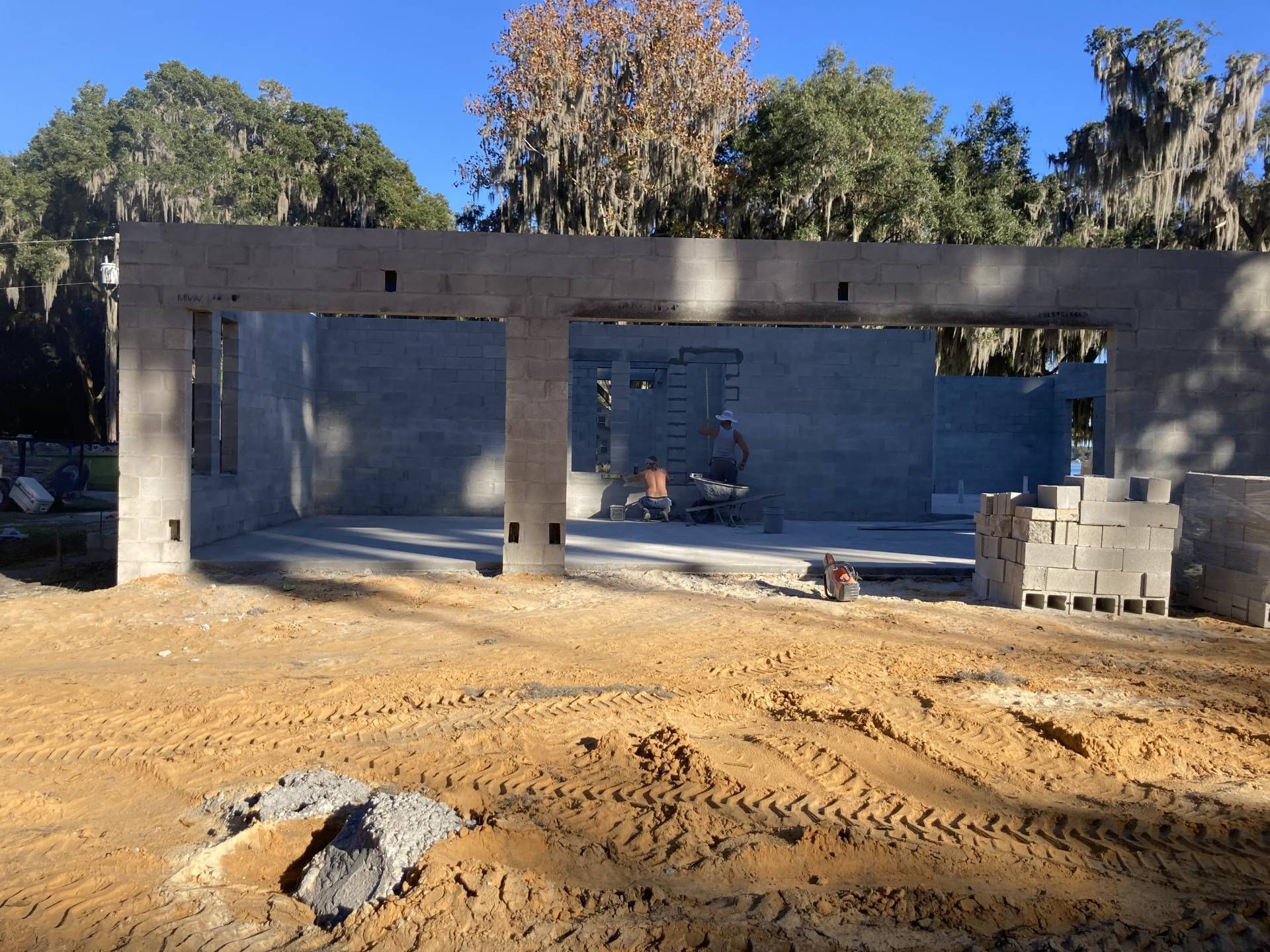 fully built masonry construction unit concrete structure on a dirt lot with trees in the background