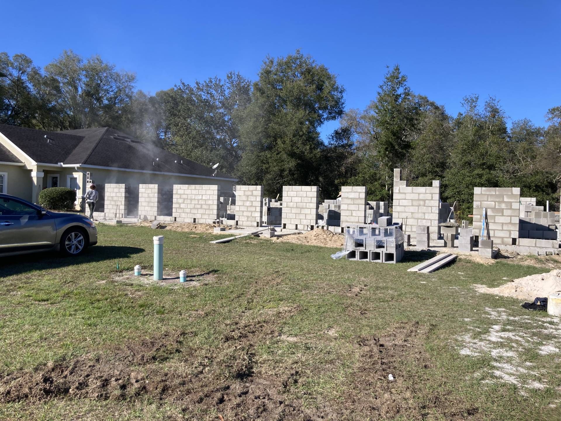 fully built concrete masonry unit block wall addition in construction in a grassy yard beside a house and truck
