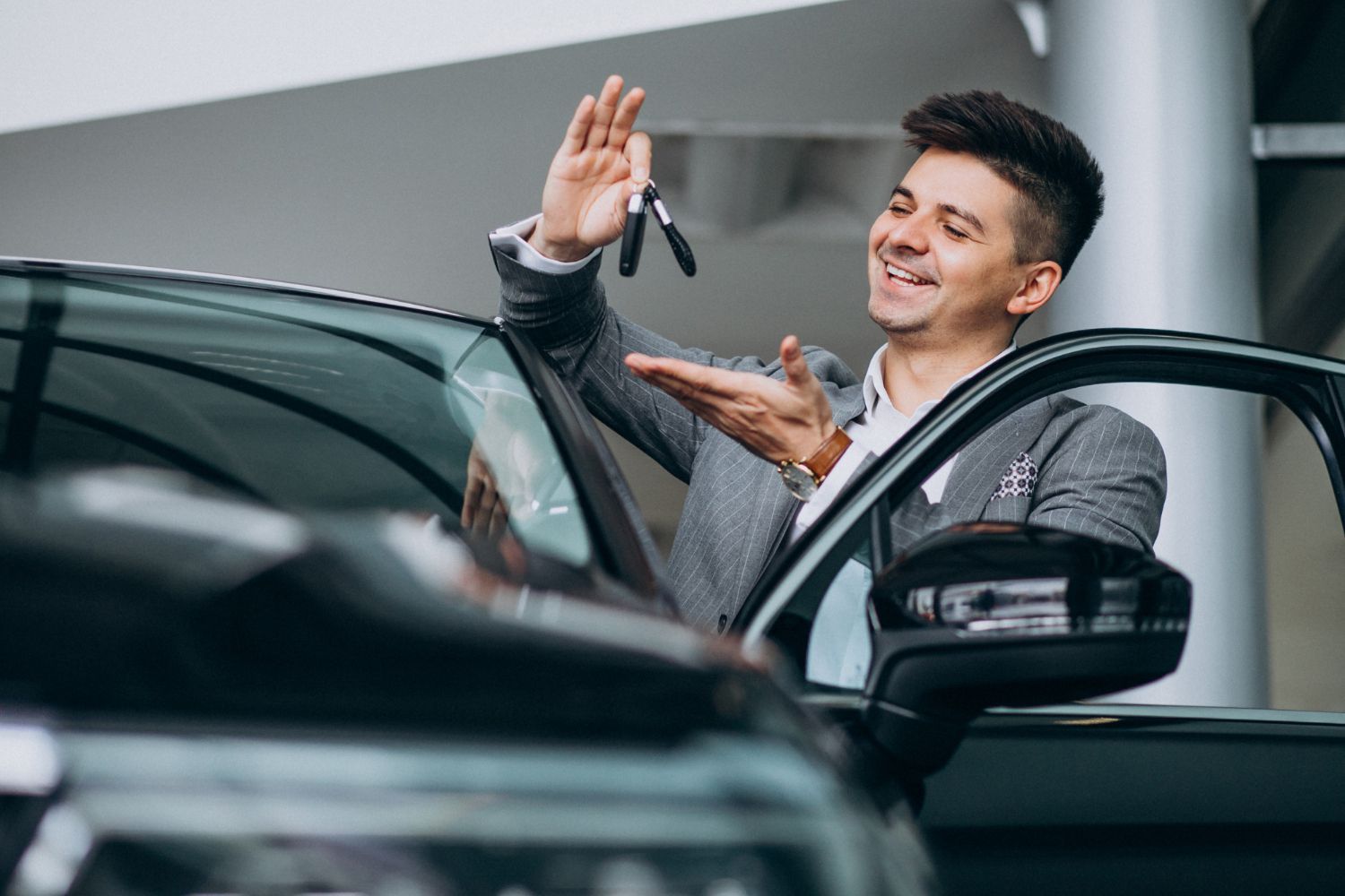 Homem sorrindo e segurando as chaves do carro ao lado de um carro novo.