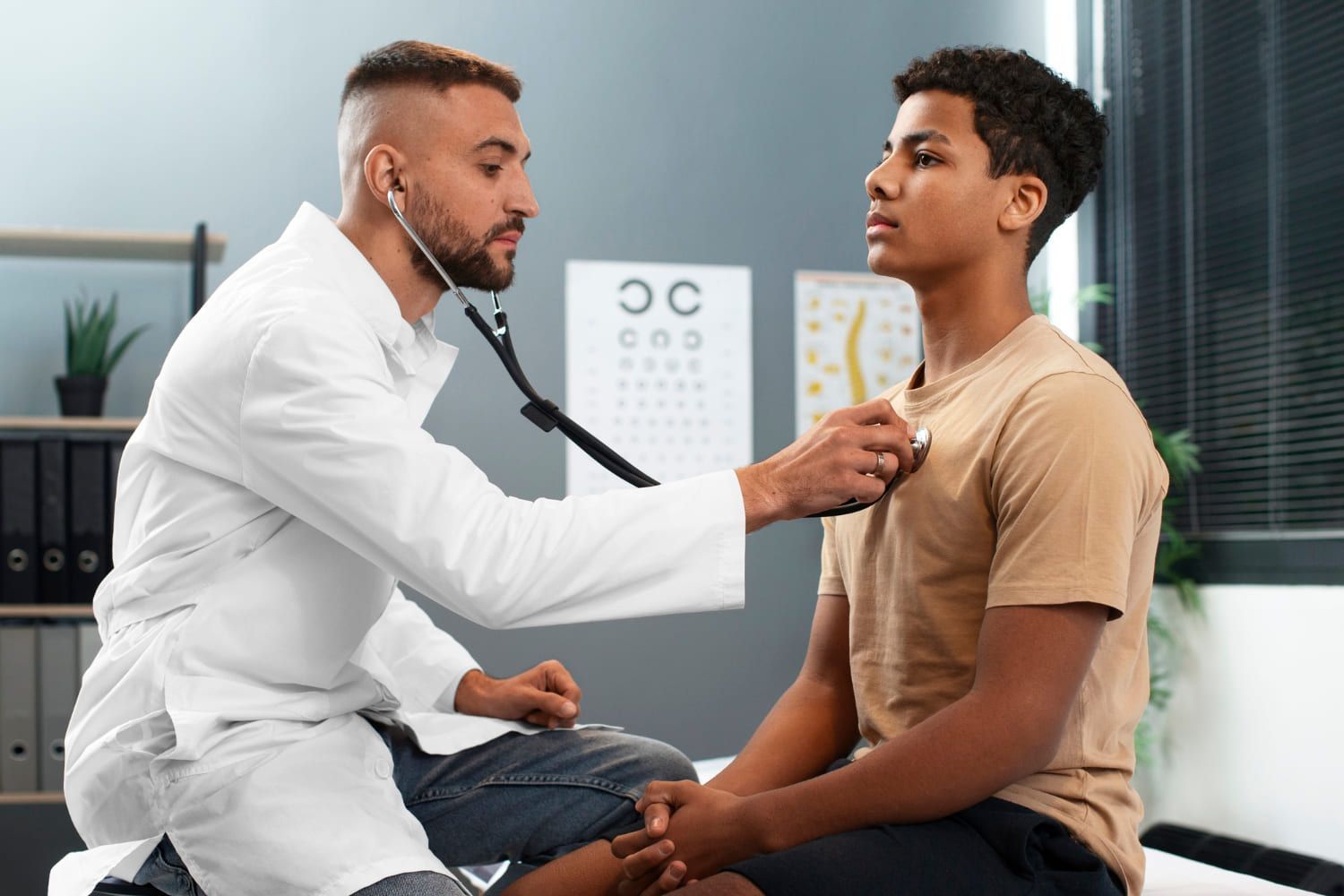 Médico usando um estetoscópio para examinar o tórax de um paciente adolescente em um consultório.
