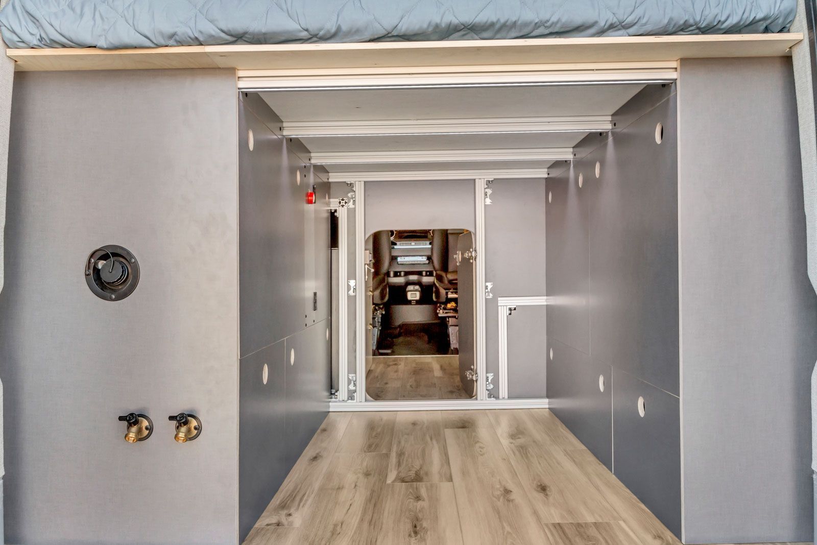Open doorway to a bright hallway under construction, with gray walls and wood flooring.