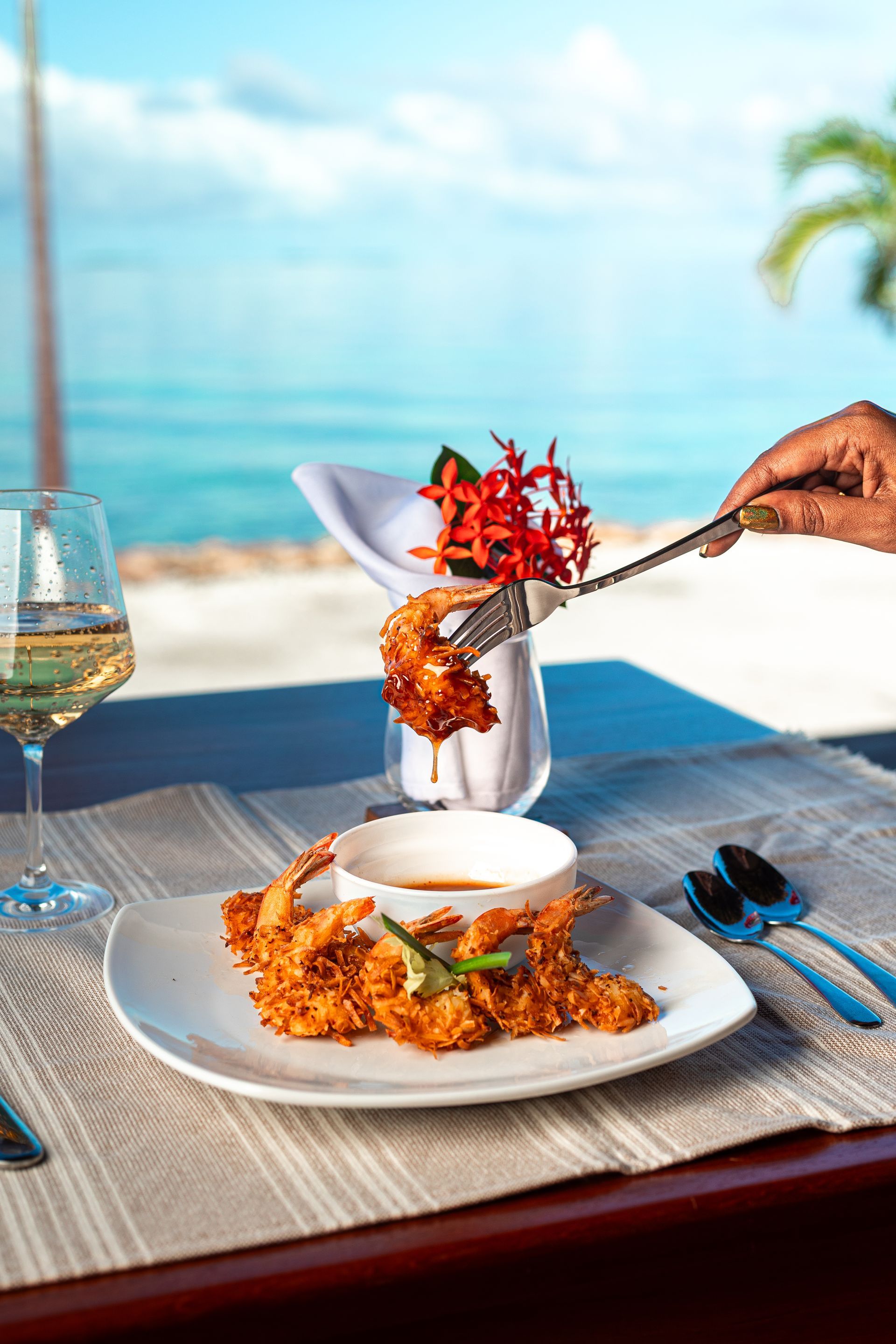 Plated seafood dish being served on a beachside table with ocean view