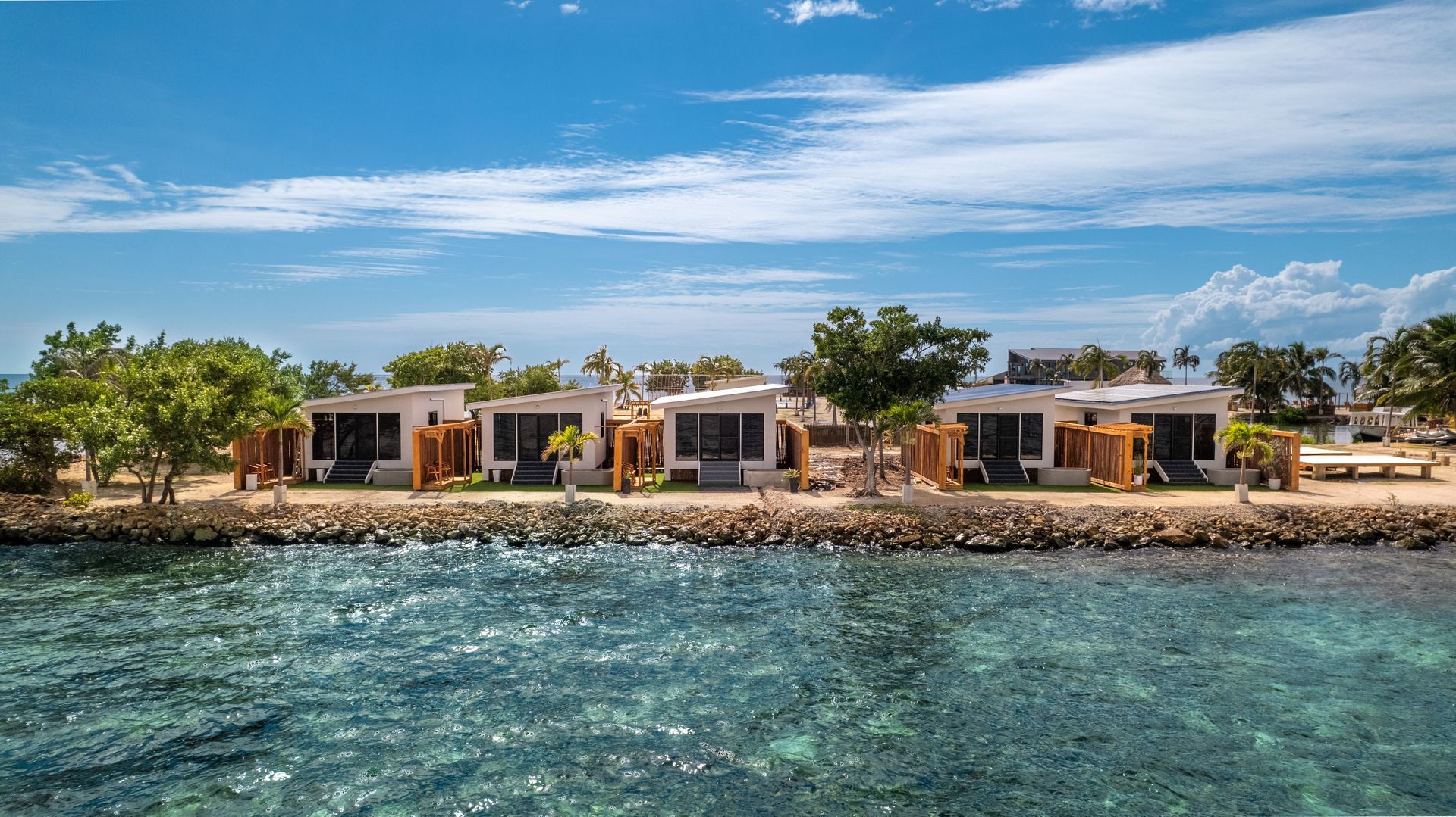 Beachfront villas beside clear blue water under a bright sky.