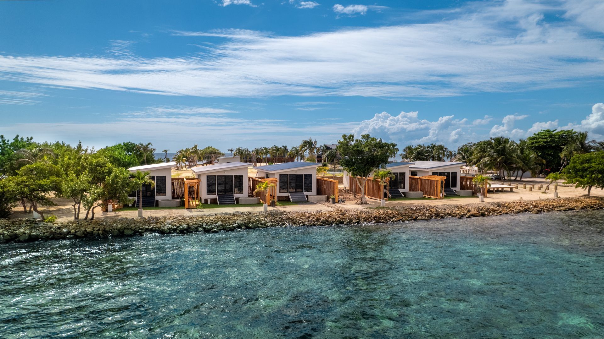 Seaside resort villas with palm trees and turquoise water under a blue sky