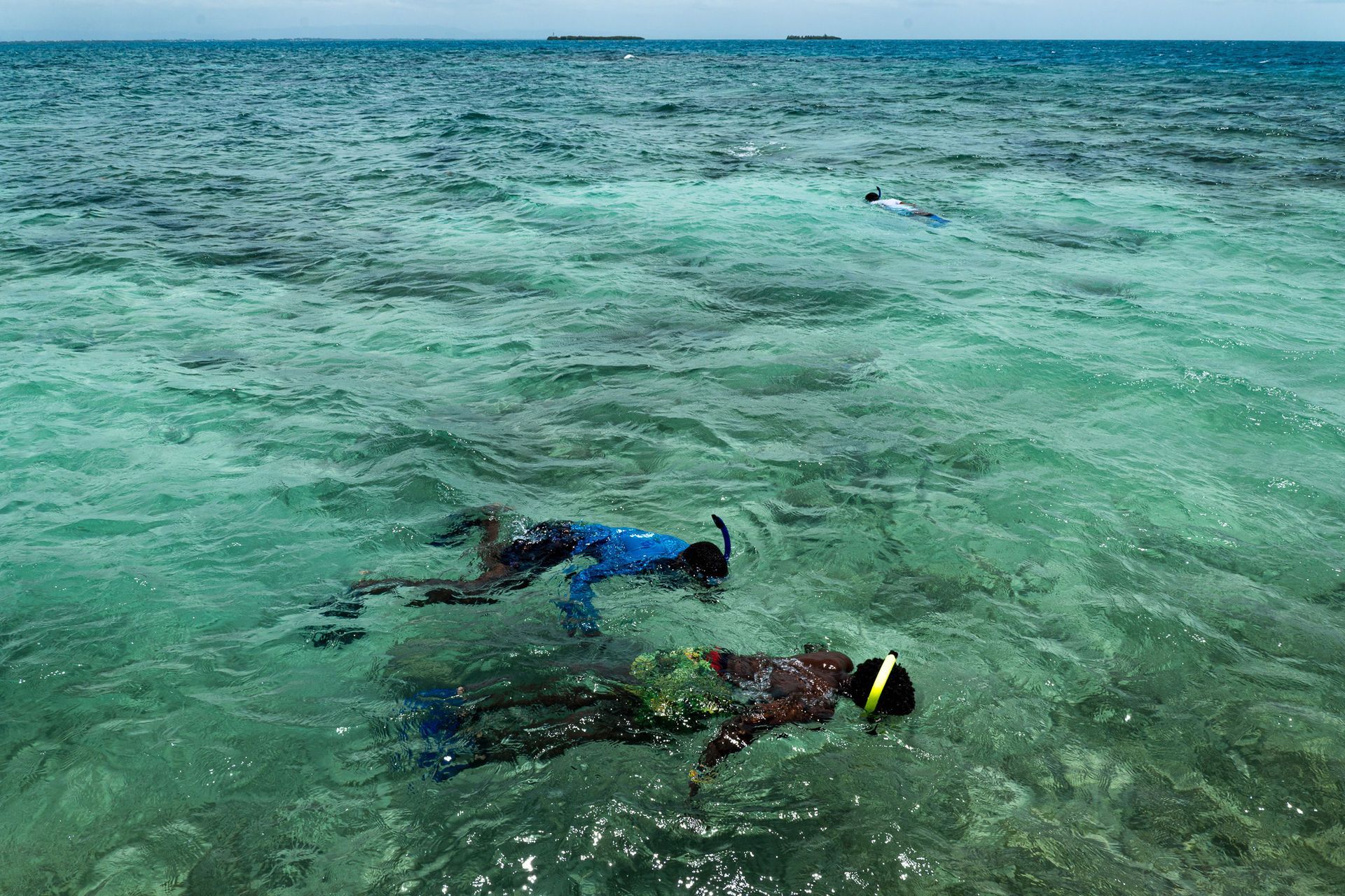 Two snorkelers floating in clear turquoise ocean water near the surface