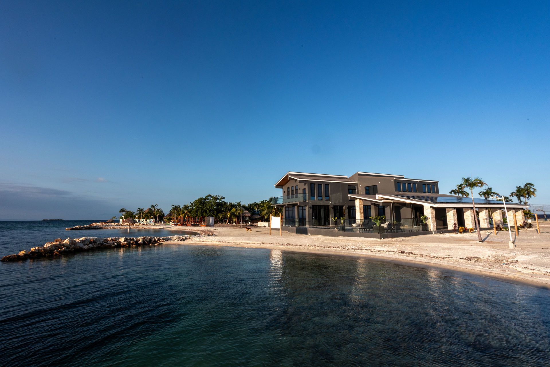 Coastal mansion with waterfront dock and calm blue sea under a clear sky