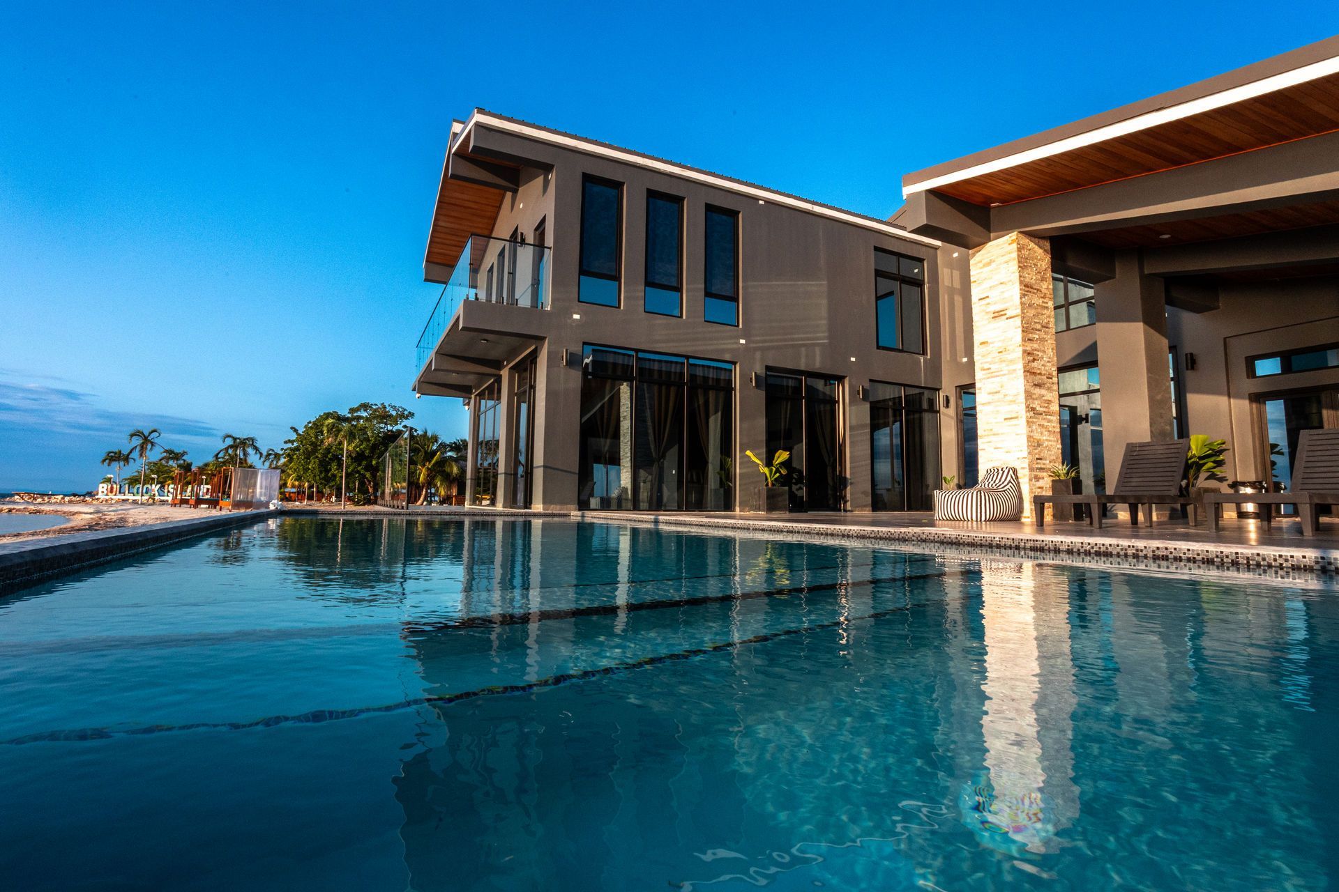 Luxury modern villa with an infinity pool overlooking the ocean at sunset