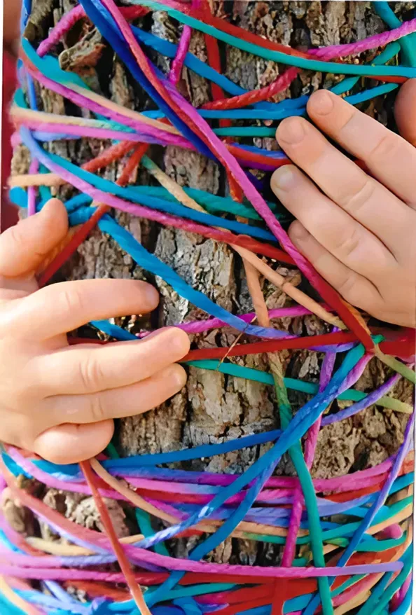 A Person Is Holding A Tree Trunk Covered In Colourful Ropes — Gap Community Early Learning Centre In The Gap, NT