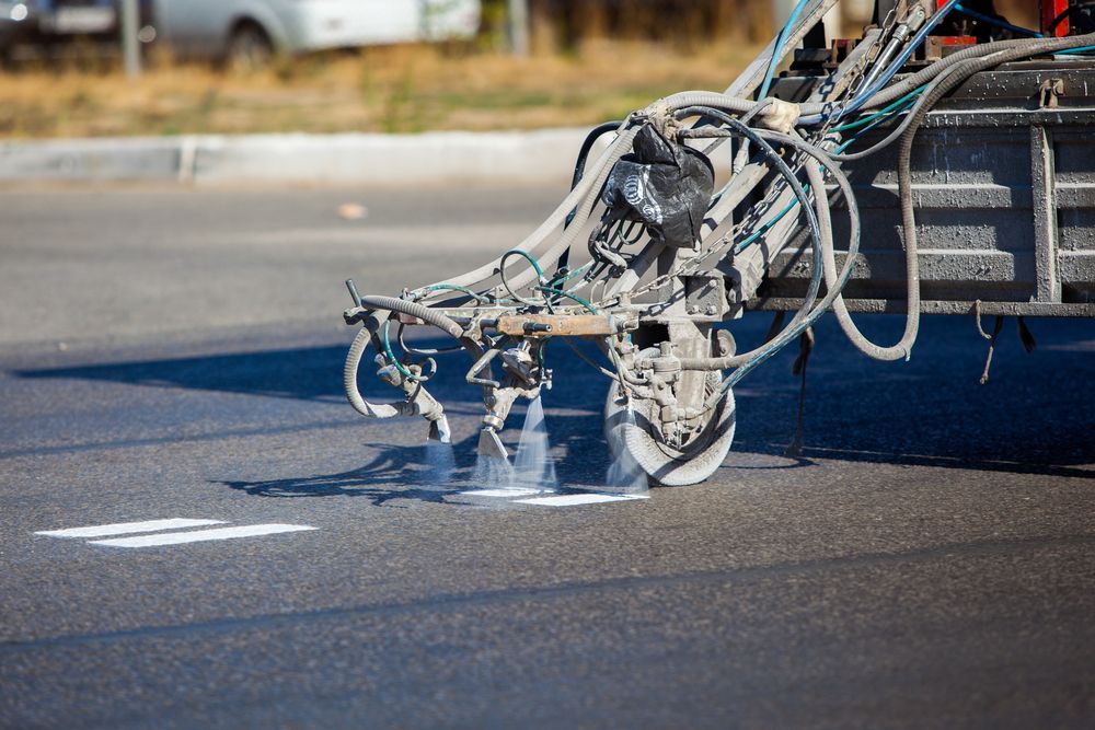 a machine is spraying white paint on a road